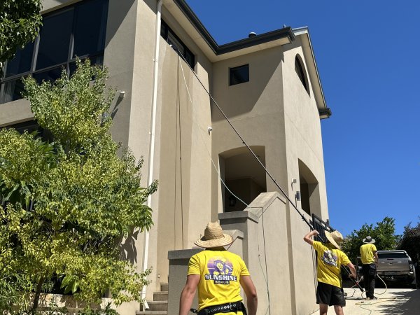 The crew water-fed pole cleaning a two-storey rendered home